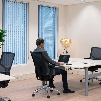 Kantoor aan de Handelsweg 53 in Amstelveen met een man die aan een bureau werkt op een laptop. Lichte, ruime werkplekken met moderne stoelen en groene planten.