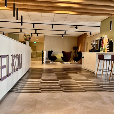 Moderne entree van een kantoorpand op Professor E.M. Meijerslaan 1 in Amstelveen. Het interieur is strak met een welkom bord en stijlvolle meubels, ideaal om als kantoorruimte te huren.