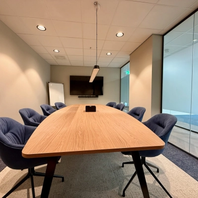 Kantoorruimte huren in Amstelveen: moderne vergaderruimte met comfortabele stoelen, houten tafel, en een flatscreen aan de muur.