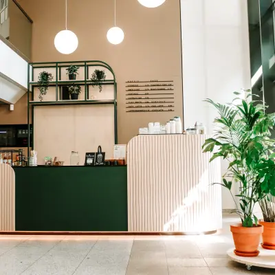 Gezellige lounge in Amstelveen met groentinten, een moderne balie en groene planten bij de ingang van een kantoorpand. Ideale plek voor kantoorruimte huren.
