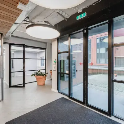 Ingang van modern kantoorpand bij H.J.E. Wenckebachweg 90-108, Amsterdam Amstel Business Park. Glazen deuren en veel licht bieden een open entree. Perfecte locatie voor wie kantoorruimte wil huren.