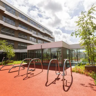 Moderne buitenruimte van kantoorpand aan Willem Fenengastraat 16, Amsterdam Amstel, met fietsenrekken en groene beplanting.