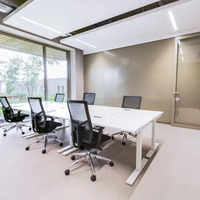 Moderne kantoorruimte huren op Willem Fenengastraat 16 in Amsterdam Amstel, met grote ramen, vergadertafel en stoelen, ideaal voor zakelijke bijeenkomsten in een lichte omgeving.