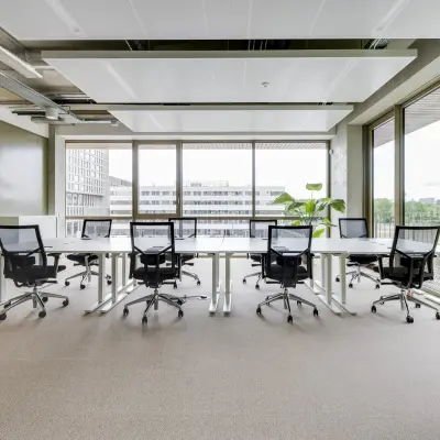 Heldere kantoorruimte met grote ramen en ergonomische bureaustoelen in Amsterdam Amstel, geschikt voor werk en vergaderingen.