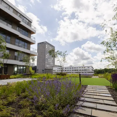 Exterieur van kantoorpand aan Willem Fenengastraat 16, Amsterdam Amstel, met moderne gebouwen en een groene tuin. Zonnige dag zonder mensen in beeld.
