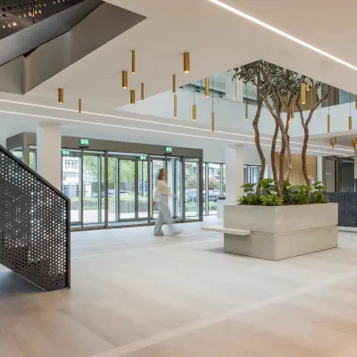 Moderne kantoorruimte te huur op Walborg 2A in Amsterdam Buitenveldert, met een stijlvolle entree, plantenbakken en een geometrisch vormgegeven trap. Ideale plek voor je volgende kantoorpand.