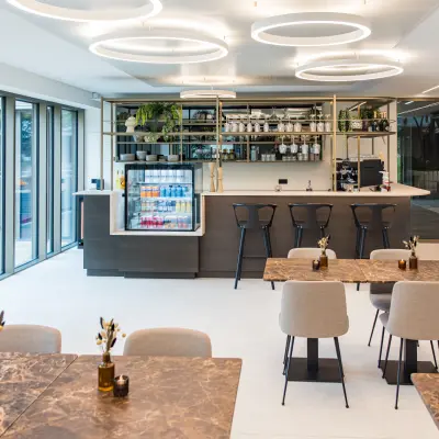 Moderne kantoorpand in Amsterdam Buitenveldert met stijlvolle inrichting en uitnodigende koffiebar. Ideale ruimte voor kantoorruimte huren met lichte tafels en hoge stoelen, klaar voor creativiteit.