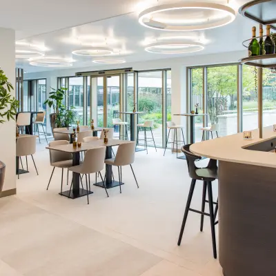 Moderne kantoorpand lounge in Amsterdam Buitenveldert aan Walborg 2A met ruime zitjes, hoge tafels en grote ramen. Ideaal voor informeel overleg of ontspanning na het huren van kantoorruimte.