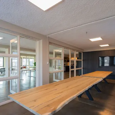 Moderne kantoorruimte te huur op Kleine Gartmanplantsoen 21, Amsterdam Centrum, met houten tafels en glazen wanden. Deze kantoorpand biedt een slimme werkruimte in het bruisende hart van de stad.