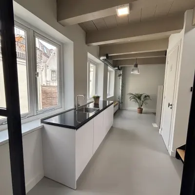 Lichte kantoorruimte te huur aan de Kloveniersburgwal 131K in Amsterdam Centrum, met moderne keuken en grote ramen. Het interieur is strak en uitnodigend.