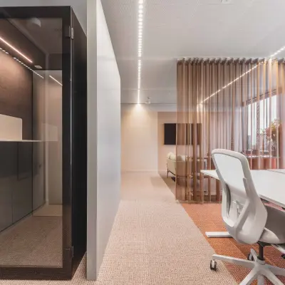 Moderne kantoorruimte huren met strakke inrichting, inclusief glazen scheidingswand en comfortabele witleren stoelen aan een vergadertafel op de Piet Heinkade in Amsterdam Centrum.