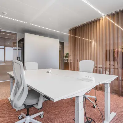 Moderne kantoorruimte voor verhuur in Amsterdam Centrum aan Piet Heinkade 55, met witte bureaus, ergonomische stoelen en glazen wanden, ideaal voor zakelijke ontmoetingen.