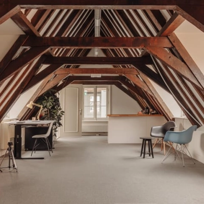 Kantoorruimte met houten balken, voorzien van enkele bureaus en stoelen, gelegen op Prins Hendrikkade 14 in Amsterdam Centrum.
