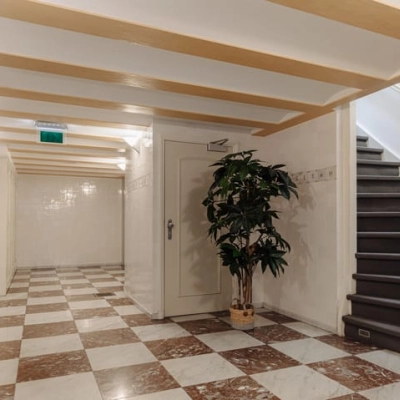 Helder verlichte gang in een kantoorpand op Prins Hendrikkade 14, Amsterdam Centrum, met marmeren vloer en planten. Ideaal voor toegang tot kantoren om te huren.