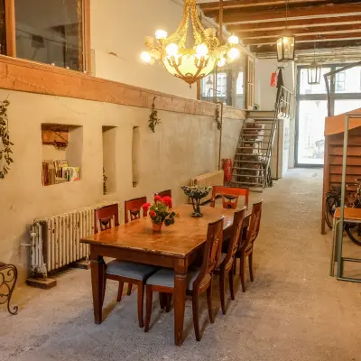 Unieke kantoorruimte huren in Amsterdam Centrum op Prinseneiland 23A. Gezellige gemeenschappelijke werkruimte met houten tafels, stoelen en decoratieve elementen. Industriële sfeer in dit karakteristieke kantoorpand.