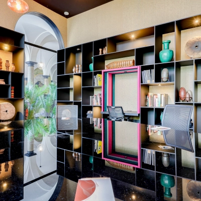 Moderne kantoorruimte huren in Amsterdam Centrum met stijlvolle inrichting, inclusief luxe bureau en designstoel. De kastenwand is gevuld met decoratie en biedt voldoende opbergruimte.