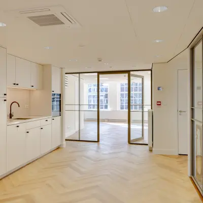 Lichte en moderne kantoorruimte op Rokin 117 117 Amsterdam Centrum met houten vloer, glazen scheidingswanden en een kleine pantry. Ideaal voor wie een kantoorpand wil huren.