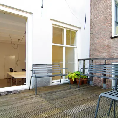 Terras van kantoorpand op Warmoesstraat 155 in Amsterdam Centrum met zicht op een vergaderruimte. Perfecte plek voor een brainstormsessie of korte pauze. Beneden kantoorruimte huren in hartje Amsterdam.