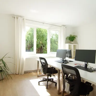 Lichte kantoorruimte huren aan de Warmoesstraat 155, Amsterdam Centrum, met grote ramen en moderne bureaus, perfect voor een inspirerende werkomgeving.