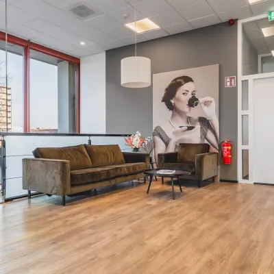 Stijlvolle kantoorruimte huren op Daalwijkdreef 47 in Amsterdam Duivendrecht met een moderne loungehoek en een grote afbeelding van een elegante dame aan de muur.