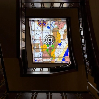 Een kleurrijk glas-in-loodraam met abstracte vormen, gevat in een donkere houten lijst, in een kantoorpand aan Herengracht 582-584, Amsterdam Grachtengordel.