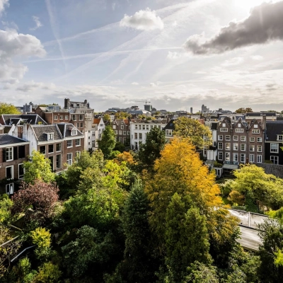Buitenzijde van kantoorpand aan de Herengracht 582-584 in de Amsterdamse Grachtengordel, met omliggende groene bomen en historische gebouwen.