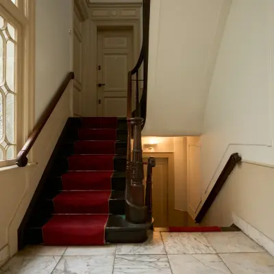 Ingang van een kantoorpand op Keizersgracht 391A, Amsterdam Grachtengordel, met rood gestoffeerde trap en marmeren vloer. Een ideale plek voor kantoorruimte huren.