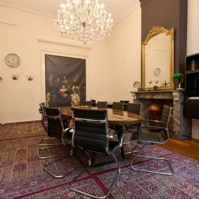 Stijlvolle vergaderruimte in een kantoorpand aan Keizersgracht 391A, Amsterdam Grachtengordel. Deze kantoorruimte huren biedt een elegante setting met moderne stoelen rond een grote tafel en een indrukwekkende kroonluchter.