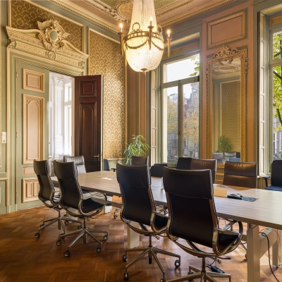 Kantoorruimte huren aan de Keizersgracht 452 in Amsterdam Grachtengordel met klassieke inrichting en chique vergadertafel met zwarte stoelen, omringd door elegante houtpanelen en grote ramen.