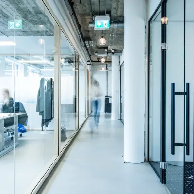 Modern kantoorpand op Singel 542 in Amsterdam Grachtengordel, met glazen wanden en zichtbare industriële elementen. Personen werken aan bureaus in een lichte ruimte.