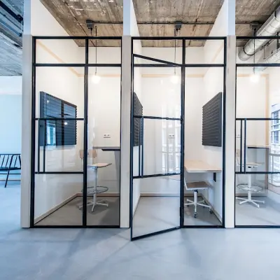 Modern kantoor met industriële elementen op Singel 542, Amsterdam Grachtengordel. Drie compacte glazen werkruimtes met bureaus en stoelen voor flexibele kantoorruimte huren.