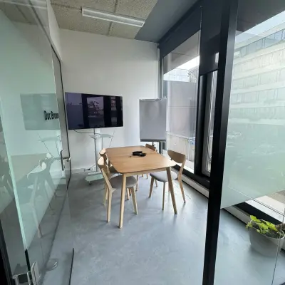 Kantoorruimte huren in Amsterdam Houthavens aan de Moermanskkade 303, met glazen wanden, houten tafel en stoelen, en een scherm, ideaal voor vergaderingen.