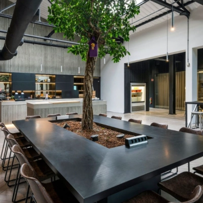 Kantoorruimte huren aan Meeuwenlaan 98-100 in Amsterdam Noord, met een grote tafel omringd door stoelen en een centrale boom, geschikt voor samenwerkingssessies.
