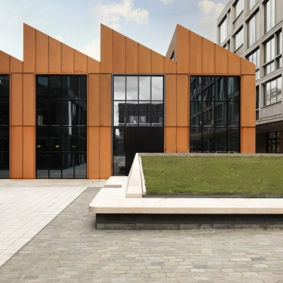 Moderne kantoorpand in Amsterdam Noord met opvallende oranje gevels en groene binnenplaats, ideaal voor kantoorruimte huren.