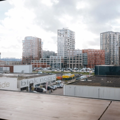 Uitzicht vanuit het kantoor op TT Vasumweg 44 in Amsterdam Noord. Het biedt een panoramisch zicht op omliggende moderne gebouwen.
