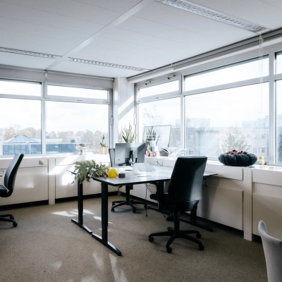 Lichte kantoorruimte op TT Vasumweg 44 in Amsterdam Noord met grote ramen, een vergadertafel en bureaus, ideaal voor het huren van een rustige en productieve werkplek.