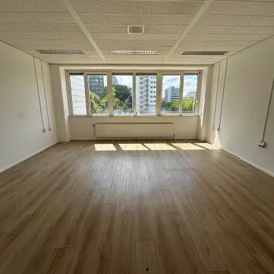 Ongemeubileerde kantoorruimte op James Wattstraat 71, Amsterdam Oost met uitzicht op de stad. Ruimte in een kantoorpand met grote ramen en houten vloer, ideaal om te huren voor een open werkplek.