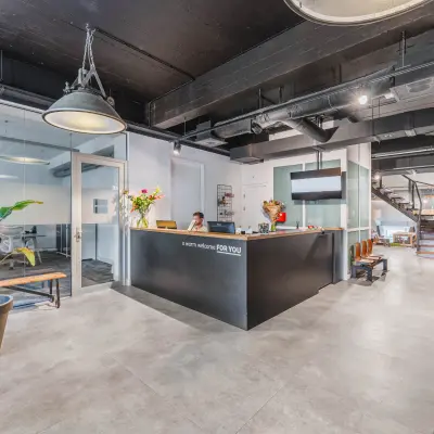 Moderne receptie met balie en ontvangstgedeelte in een kantoorpand op Olympisch Stadion 24-28, Amsterdam Oud Zuid. Een vrouw zit achter de balie en verwelkomt bezoekers.