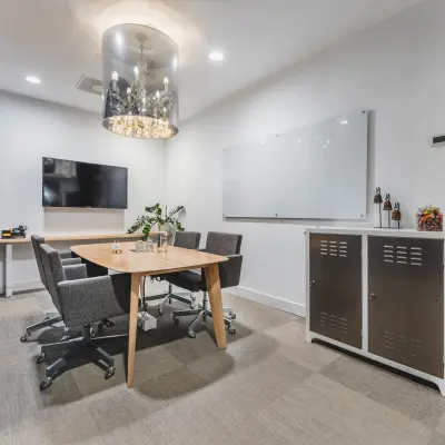 Moderne kantoorruimte huren in Amsterdam Oud Zuid, kantoorpand met vergadertafel, stoelen, televisie en groene wanddecoratie.