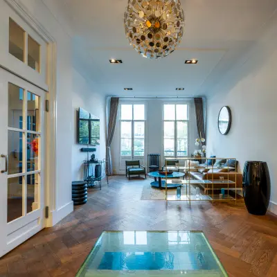 Stijlvolle kantoorruimte huren op PC Hooftstraat 150, Amsterdam Oud Zuid, met houten vloer, moderne inrichting en grote ramen, ideaal voor zakelijke ontmoetingen.