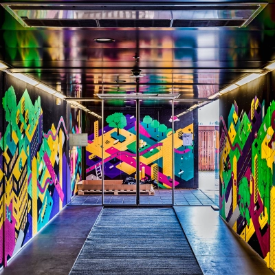 Ingang van het kantoorpand op Johan Huizingalaan 400, Amsterdam Riekerpolder, met kleurrijke muurschilderingen. Ideale plek voor bedrijven die kantoorruimte zoeken in een inspirerende omgeving.