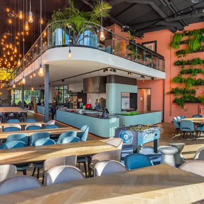 Moderne en ruime kantoorruimte op John M. Keynesplein 4-10 in Amsterdam Riekerpolder met gemeubileerd interieur, plantenwand en speelse verlichting, ideaal om een kantoor te huren voor zakelijke activiteiten.