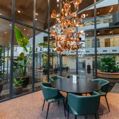 Moderne kantoorruimte op John M. Keynesplein 4-10, Amsterdam Riekerpolder, met een glazen wand, groene planten en een ronde tafel met stoelen voor vergaderingen.