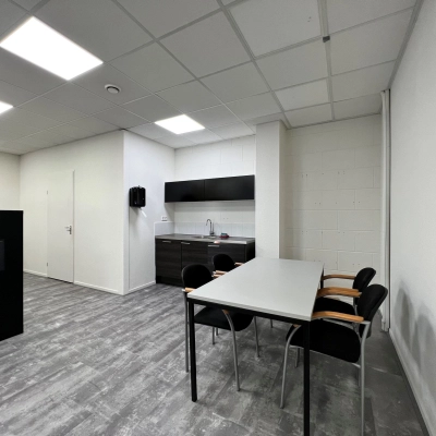 Moderne kantoorruimte huren aan de Contactweg 131 in Amsterdam Sloterdijk, met strakke vloeren, witte muren en een kitchenette met stoelen, ideaal voor diverse zakelijke activiteiten.