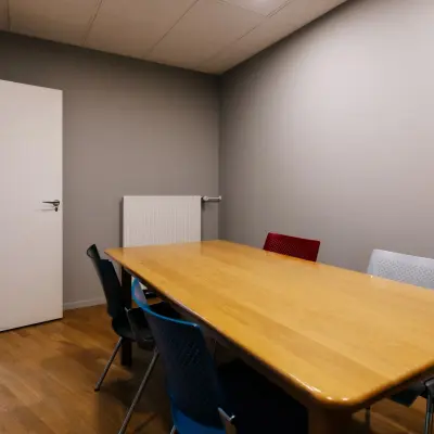 De kantoorruimte op Kabelweg 24 in Amsterdam Sloterdijk heeft een vergaderruimte met een houten tafel en kleurrijke stoelen, ideaal voor wie kantoorruimte wil huren in een professioneel kantoorpand.