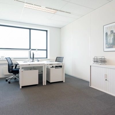 Goed verlichte kantoorruimte huren aan Teleportboulevard 110 in Amsterdam Sloterdijk met strak interieur, twee bureaus en een grote raam. Ideaal voor een productieve werksfeer in een kantoorpand.