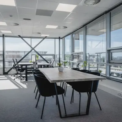 Moderne kantoorruimte te huur in Amsterdam West met grote ramen voor natuurlijk licht, voorzien van tafel en stoelen voor vergaderingen.