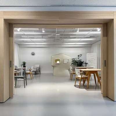 Moderne kantoorruimte op Haarlemmerweg 331 in Amsterdam West, ideaal voor het huren van een creatieve werkplek. Ruimte met houten accenten, tafels, stoelen en diverse werkstations.