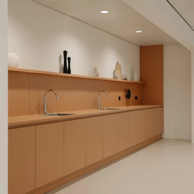 Moderne pantry met bruin-oranje kasten en dubbele wasbak in kantoorpand aan Nachtwachtlaan 20, Amsterdam West.