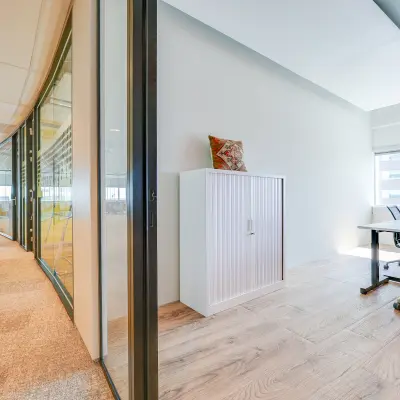 Moderne kantoorruimte met glazen wanden en houten vloer aan De Entree 99-197 in Amsterdam Zuid-Oost, ingericht met bureau en kast, beschikbaar voor kantoorruimte huren.